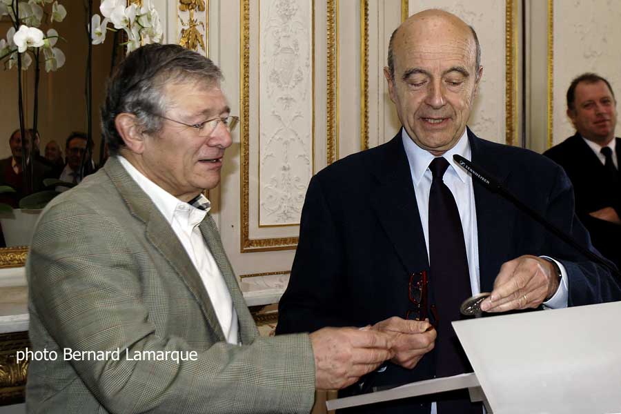 Michel Iturria découvre la médaille de la ville de Bordeaux que lui montre Alain juppé